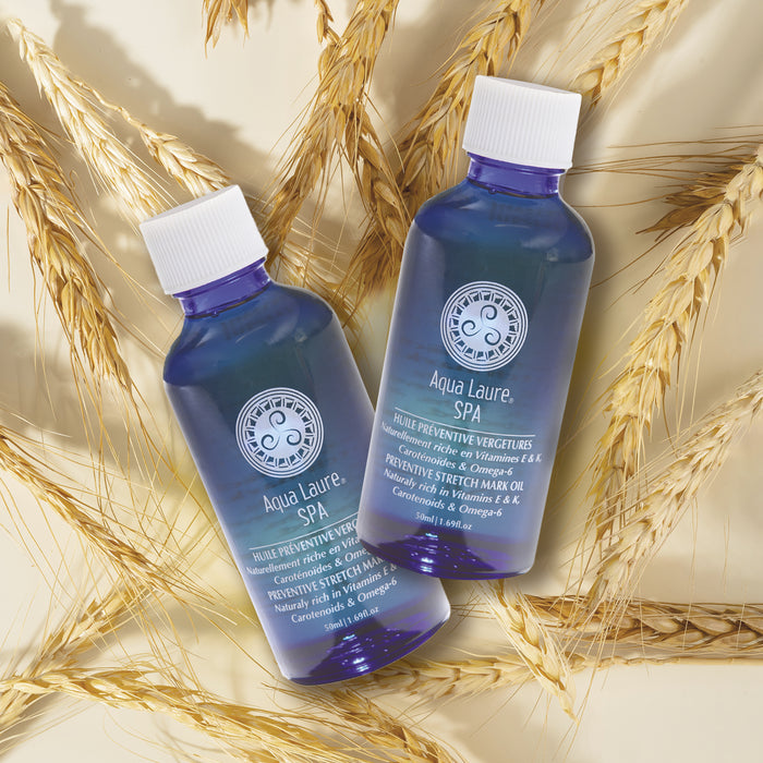 Two blue Aqua Laure SPA bottles of preventive stretch mark oil with wheat stalks, rich in Vitamins E & K, carotenoids, and Omega-6.