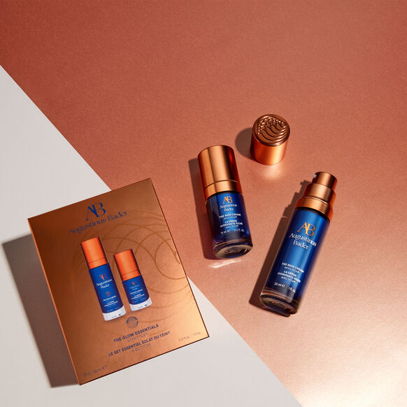 Augustinus Bader The Glow Essentials skincare set with two blue and copper bottles and gift box