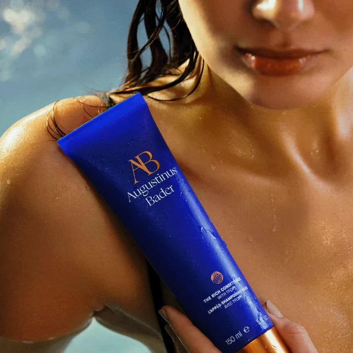 Augustinus Bader The Rich Conditioner blue tube on model's shoulder