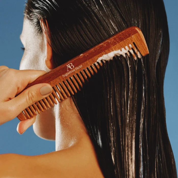 Wooden Augustinus Bader comb applying rich conditioner through sleek dark hair