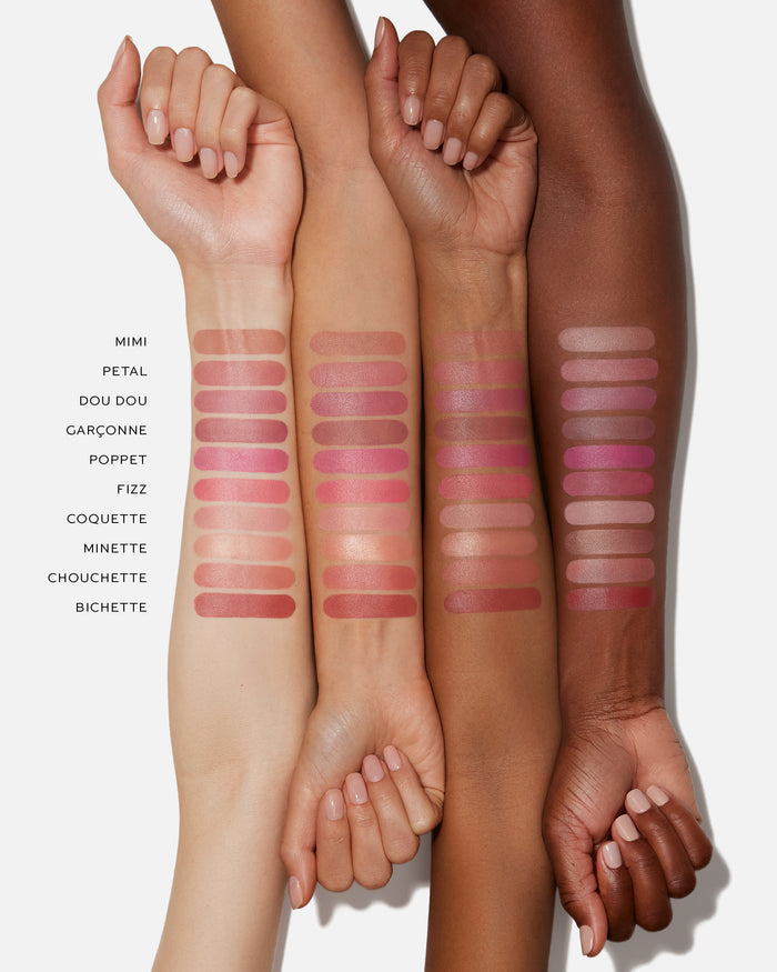 Four arms with different shades of pink lipsticks swatched on a white background.