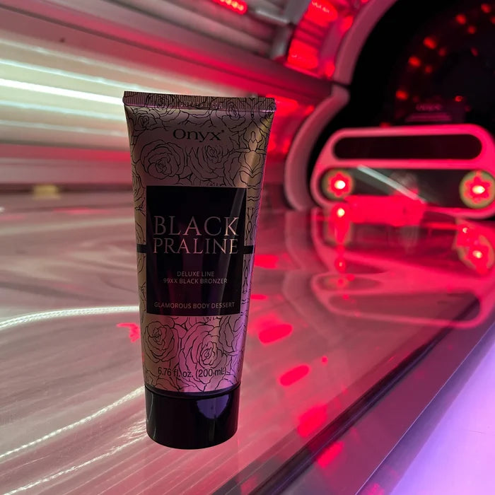 Tuba balsamu Onyx Black Praline ustawiona w kabinie solarium o czerwonym świetle