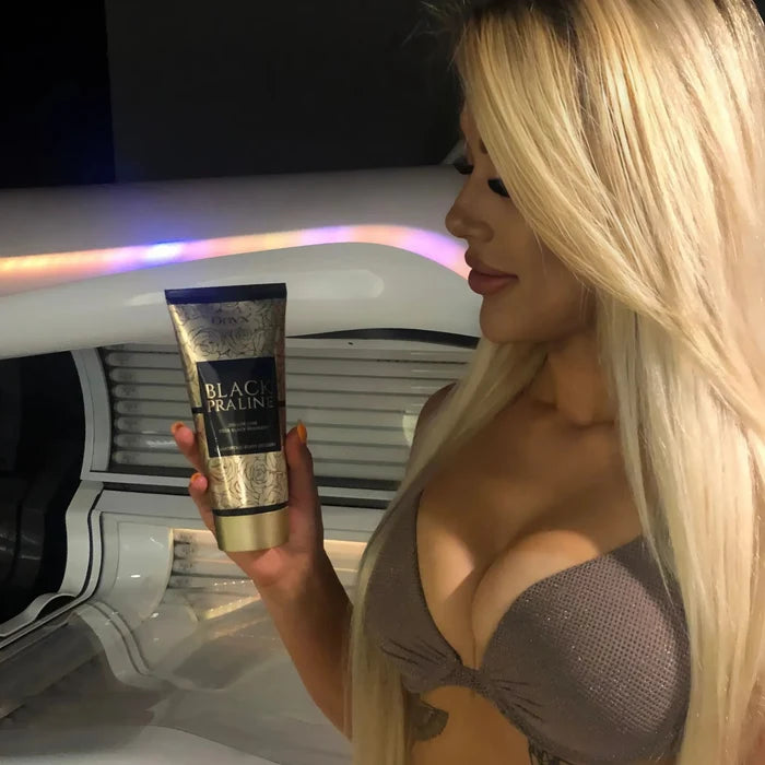 Blondynka w brązowym bikini trzyma balsam Onyx Black Praline i stoi obok łóżka w solarium