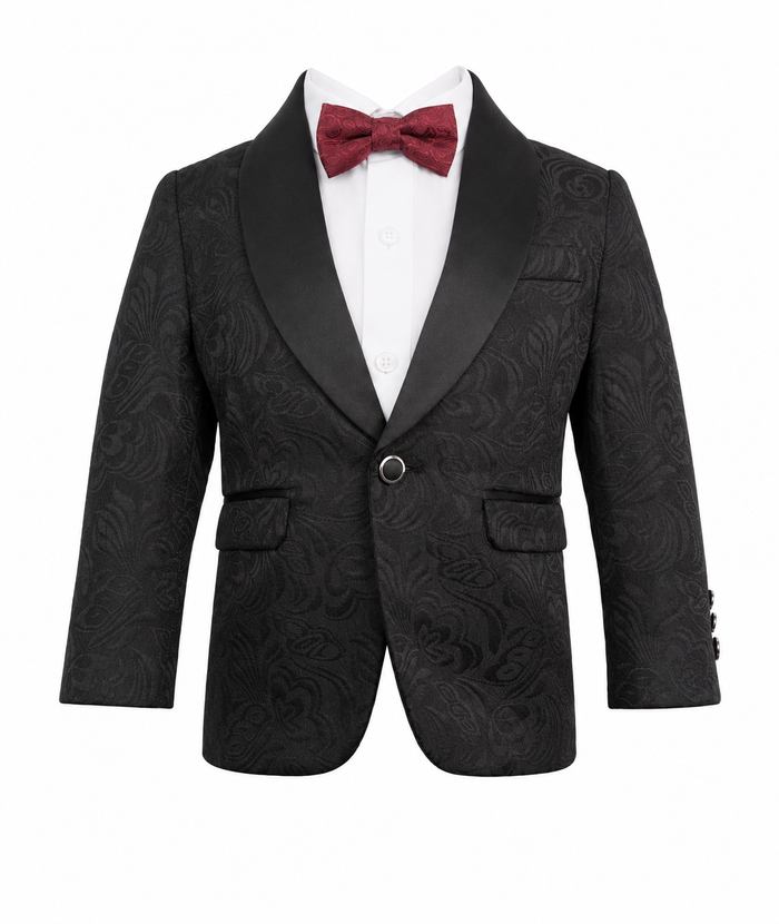 A boy's formal tuxedo jacket in black textured jacquard with satin shawl lapels, styled with a white dress shirt and a burgundy bow tie on a white background.