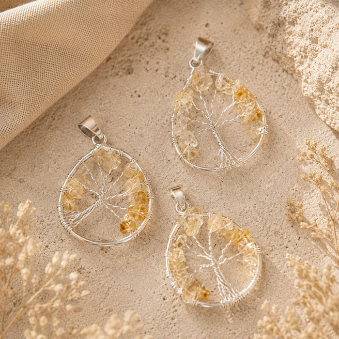 Citrine Tree of Life pendants with natural citrine gemstone chips and silver wire tree designs on a textured stone background.