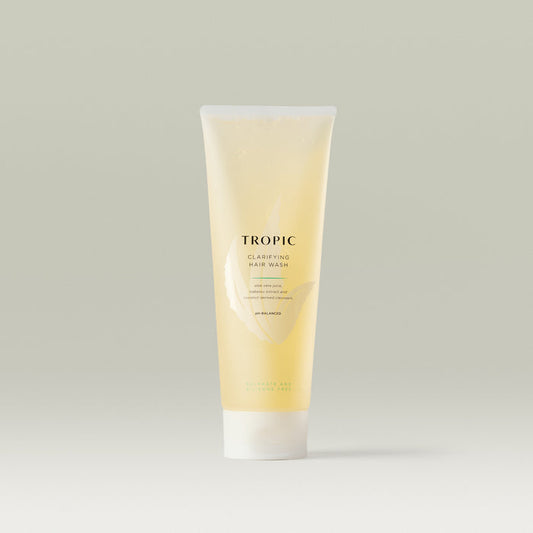 Tropic Clarifying Hair Wash in a translucent golden tube with white cap, featuring minimalist branding. The gentle formula with aloe vera juice, babassu extract, and coconut-derived cleansers is designed for a sulphate- and silicone-free deep clean.