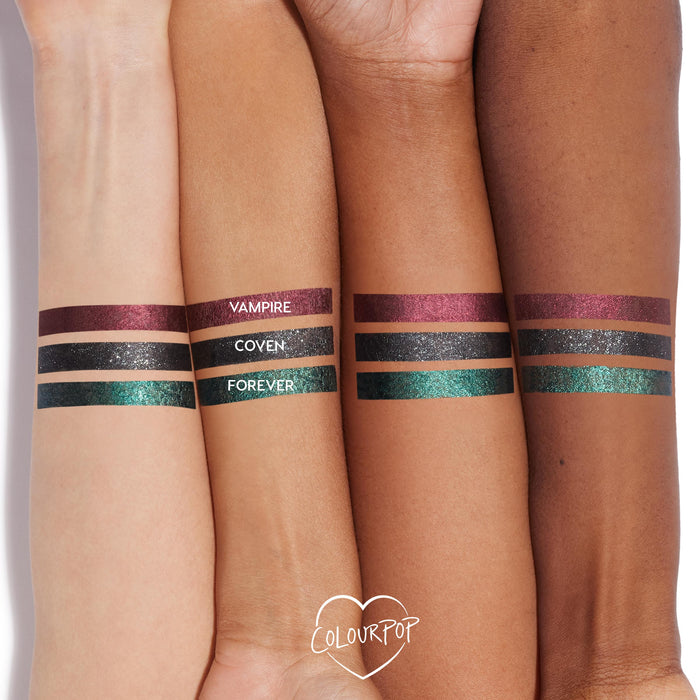 ColourPop Coven Graphix Ink Liner swatched on three forearms - a sparkly charcoal-black stripe centered between metallic burgundy Vampire and emerald-teal Forever - showing opaque payoff across multiple skin tones; ColourPop heart logo below.