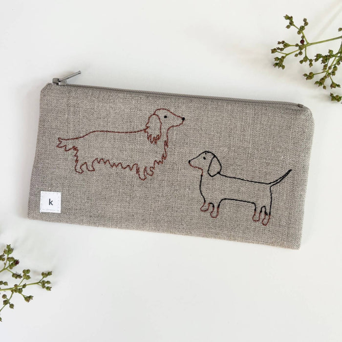 Small gray linen pouch with zipper and red dachshund embroidery, front tag detail.