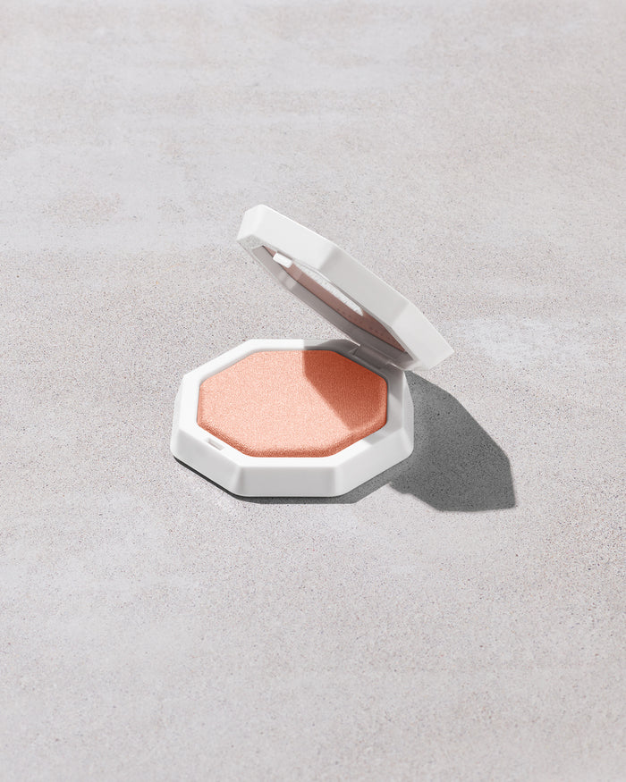 Open product shot of Demi'glow Light-Diffusing Highlighter in shade Tutu Much on a concrete backdrop.