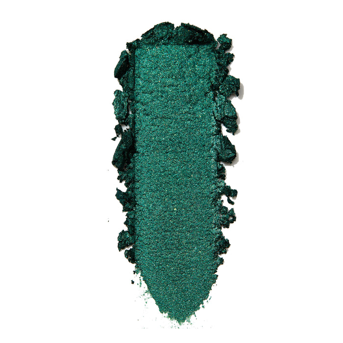Empire Super Shock Shadow by ColourPop swatched in a single elongated smear, showing a rich metallic emerald green with fine shimmer and soft crumbled edges on a white background to highlight texture and pigment payoff.