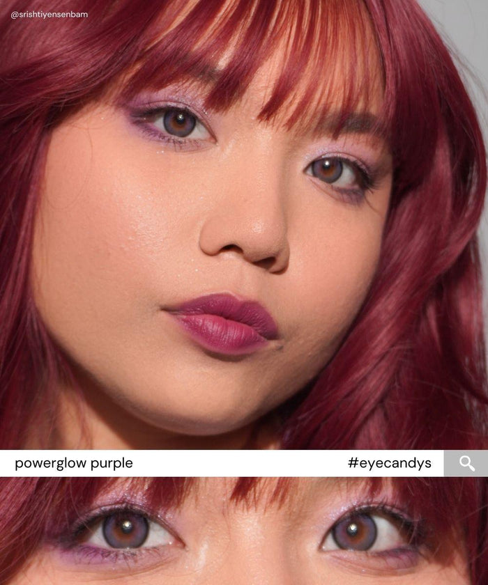 A woman with reddish-purple hair, purple eye makeup, and lipstick wears EyeCandys Powerglow Bluish Purple contact lenses. The close-up highlights her glowing skin and brown eyes. A zoom of her eyes reads: "EyeCandys Powerglow Purple #eyecandys.