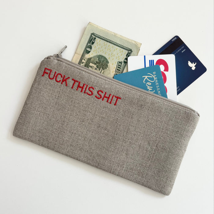 Small gray zippered pouch holding cards and cash in view