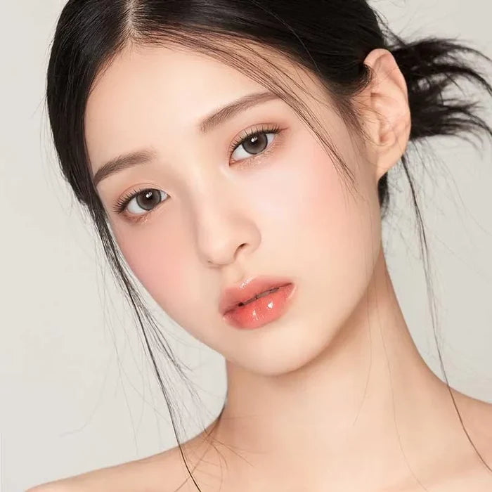 A young woman with fair skin and straight dark hair wears Gemhour Demeter 1-Day 13.0 Pebble Grey (10pk) contact lenses, looking at the camera against a plain light background.