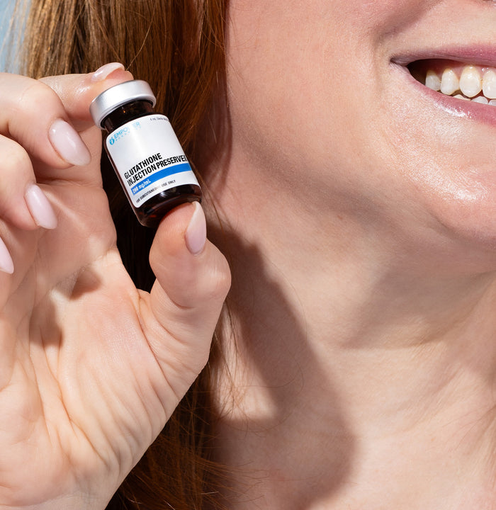 Person holding a vial labeled 'Glutathione' close to their face.