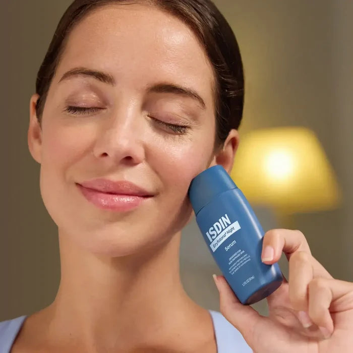 Woman holding ISDIN Eryfotona Night serum bottle for overnight sun damage repair