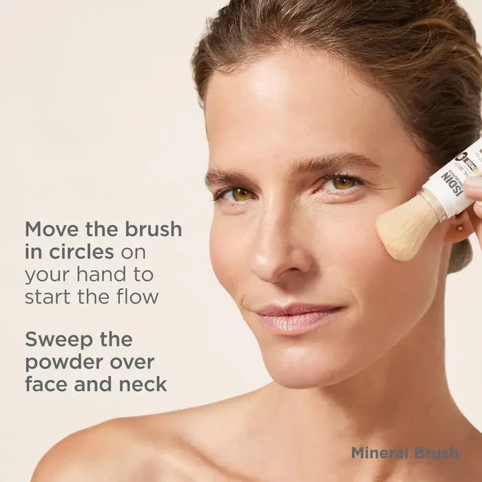 Woman applying ISDIN Mineral Brush powder to face with instructions text