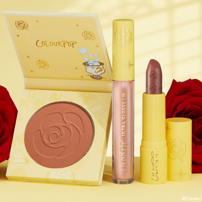 Kind at Heart ColourPop Lip & Cheek Set displaying an open yellow blush compact with rose embossing, a shimmery pink Ultra Glossy Lip, and an uncapped mauve lipstick, styled on a sunny yellow backdrop with rose and Chip graphics and red roses.