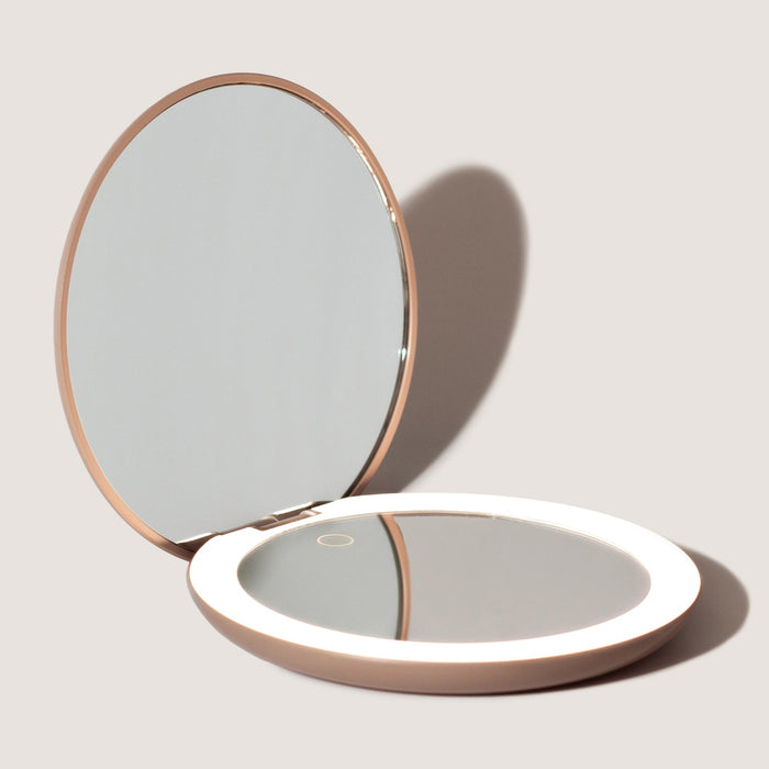 Open compact mirror with LED lights on a neutral background