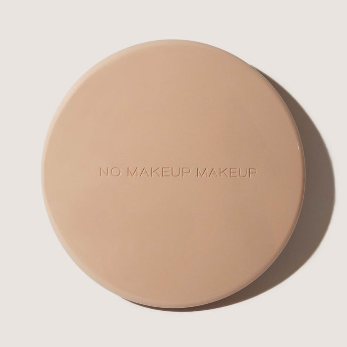 No Makeup Makeup written on a round beige compact on a light gray background