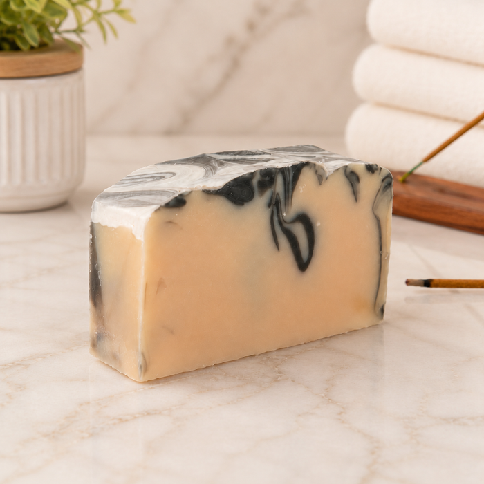 Marble-patterned goat milk soap bar on a marble surface with a blurred background