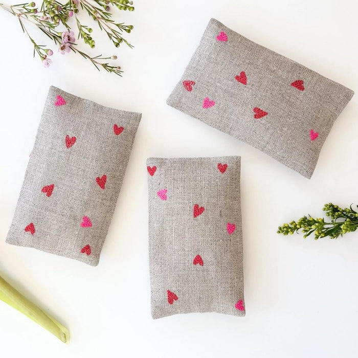 Gray fabric sachet pouches with small red and pink micro hearts, set of three.
