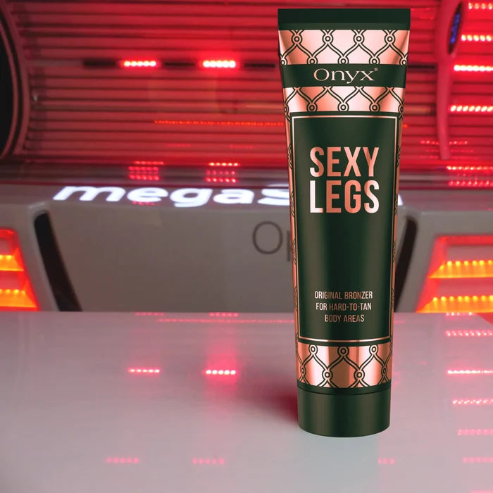 Tuba balsamu Onyx Sexy Legs stoi na powierzchni przy urządzeniu solaryjnym o czerwonym świetle