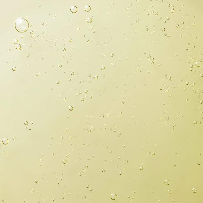 Close-up texture of Tropic's signature hand wash with golden liquid and small bubbles suspended throughout.