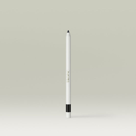 A white pencil-style eyeliner with a black tip and a black band near the base, shown standing upright against a soft, neutral background.