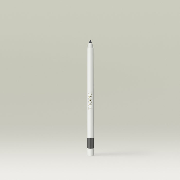 A white pencil-style eyeliner with a soft grey tip and a grey band near the base, shown standing upright against a soft, neutral background.