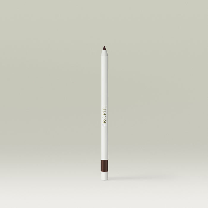 A white pencil-style eyeliner with a deep brown tip and a matching brown band near the base, shown standing upright against a soft, neutral background.