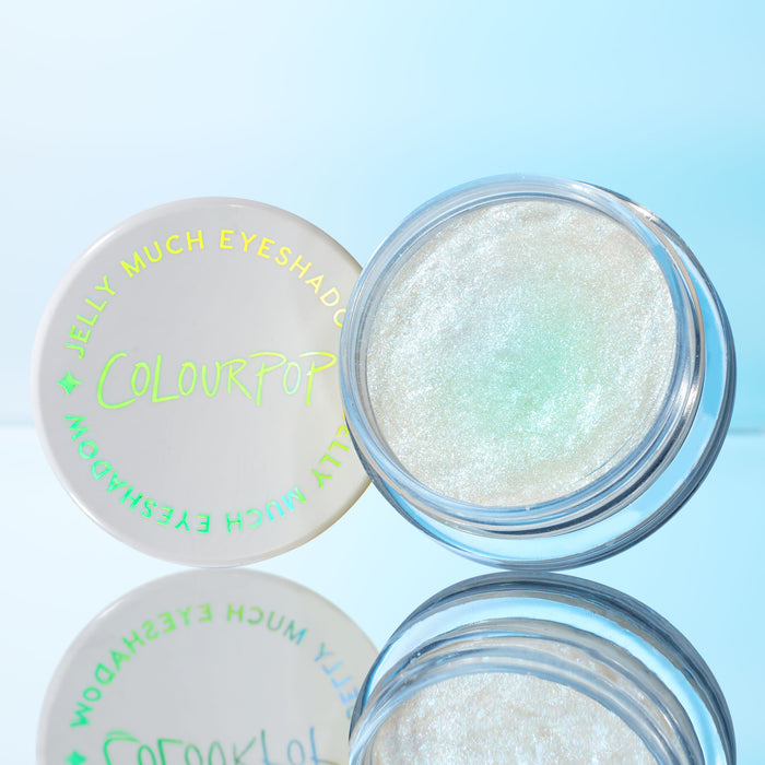 Open pot displays Super Cool ColourPop Jelly Much Shadow, a glistening icy white gel eyeshadow with a mint-green shift, with the ColourPop lid angled beside it on a reflective blue surface.