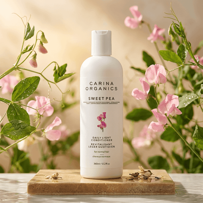 Carina Organics Sweet Pea skincare product on a wooden board with flowers in the background