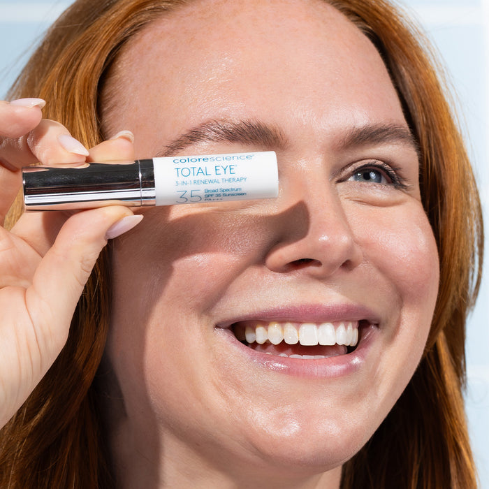 Woman holding a Colorescience Total Eye product close to her eye