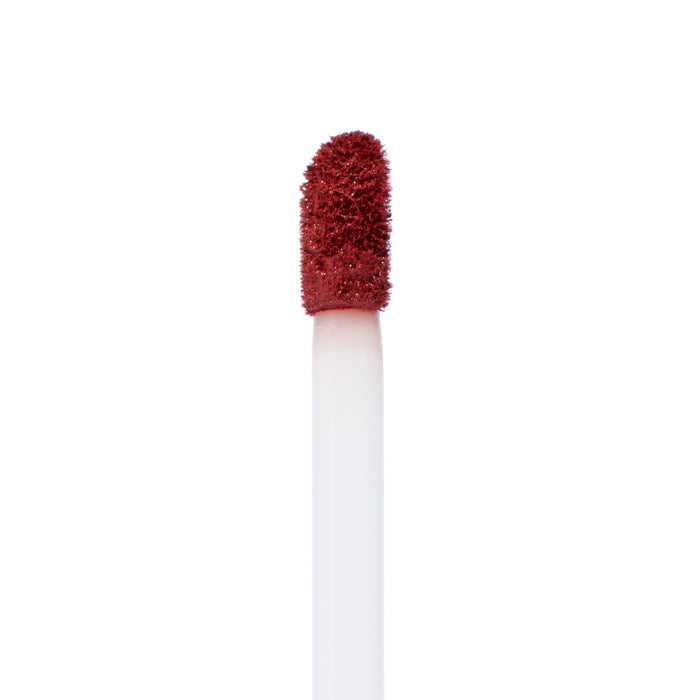 Doe-foot applicator coated in Tulum, a warm terracotta red from ColourPop Ultra Matte Lip, showing velvety texture on a white wand in a crisp macro close-up against a plain white background.