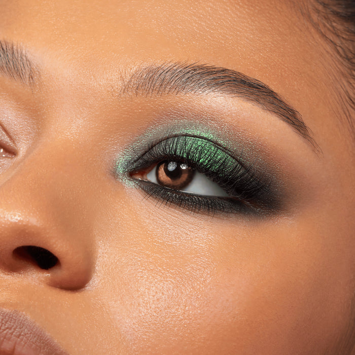 Smoky emerald eyeshadow sweeps across a brown eye with black liner and full lashes, showcasing metallic teal shimmer from the Twilight Shadow Palette, a ColourPop Shadow Palette, in a studio close-up with defined brow and warm skin.